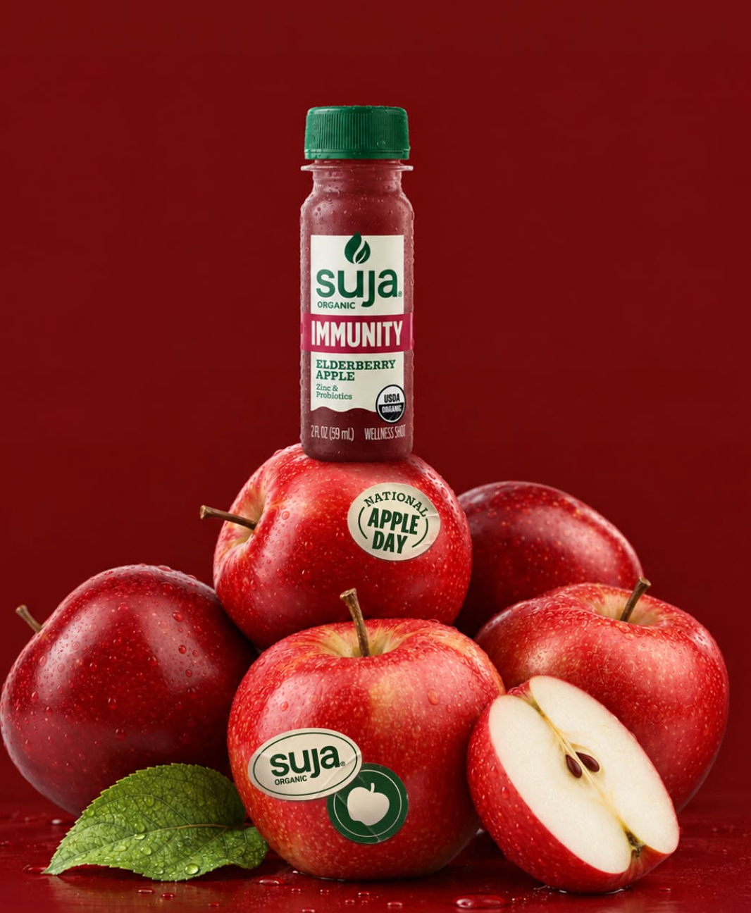 Frasco Suja Organic Immunity Elderberry Apple sobre maçãs vermelhas.
